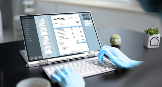Facture affichee a l'ecran d'un ordinateur portable sur le bureau d'une agence immobiliere