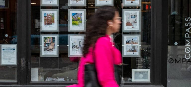 Jeune femme passant devant une agence immobilière à New York aux Etats-Unis