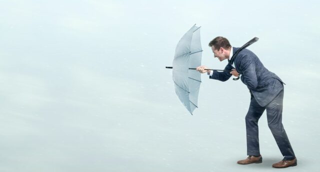 Un homme résiste au vent avec son parapluie