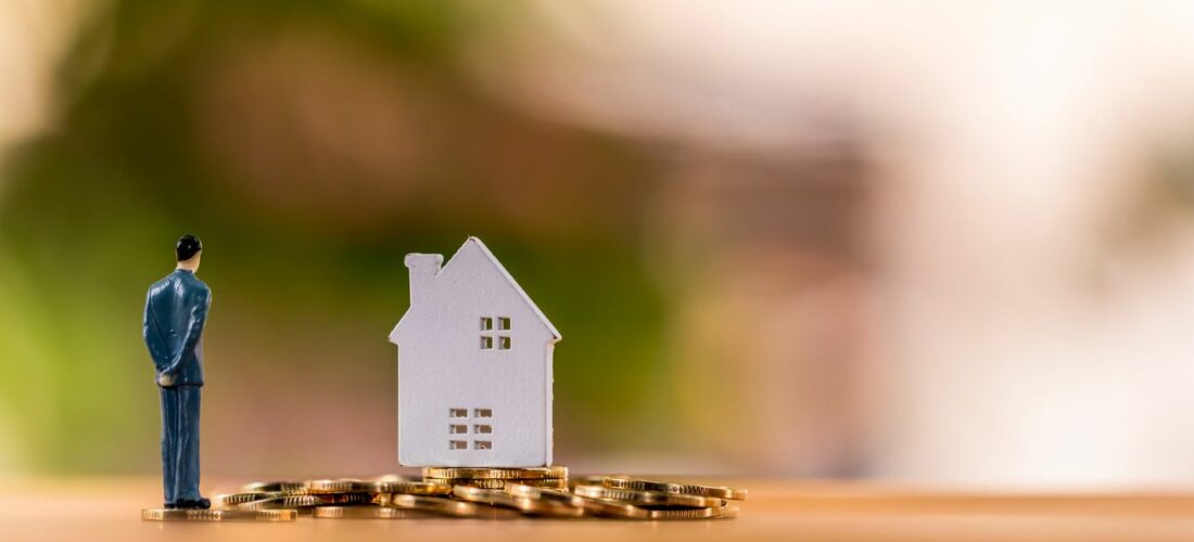 Figurine agent immobilier et maison, et des pièces d'euros.