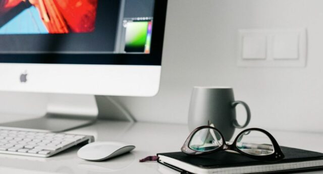 Espace de travail maison avec ordinateur, café, lunettes, cahier