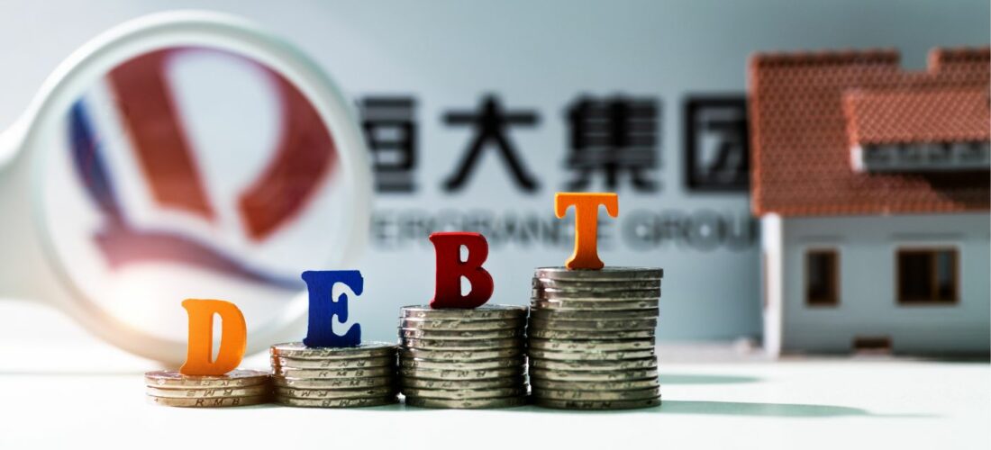 logo evergrande, loupe, pièces de monnaies et le mot dette