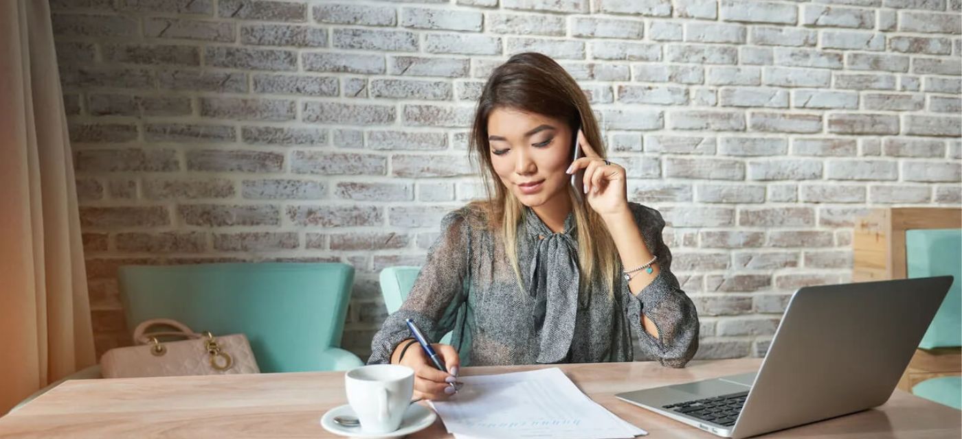 Jeune femme au telephone devant son ordinateur