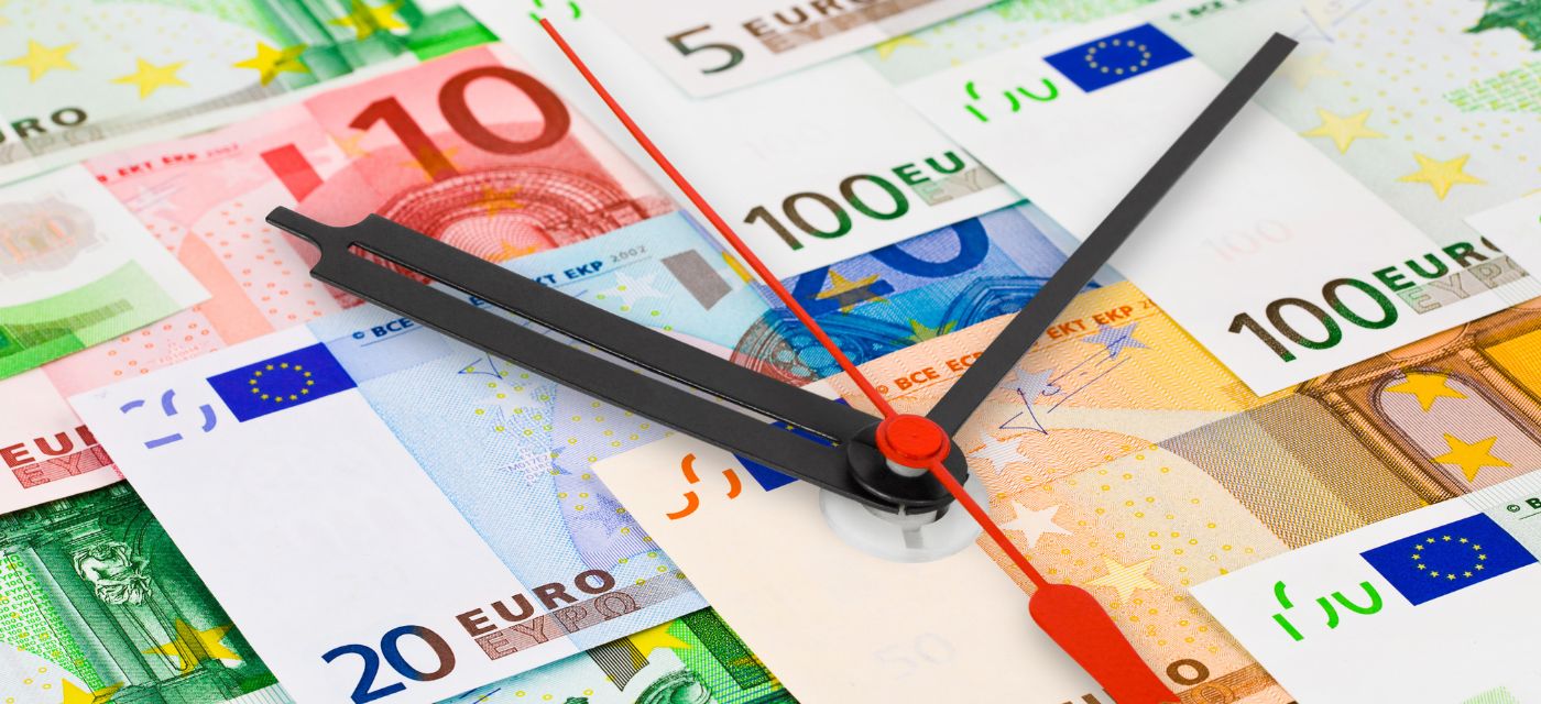 Des aiguilles d'horloge posées sur des billets d'euros