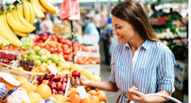 Jeune femme achetant des fruits au marché