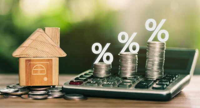 une petite maison, une calculette, des euros et des pourcentages à la hausse