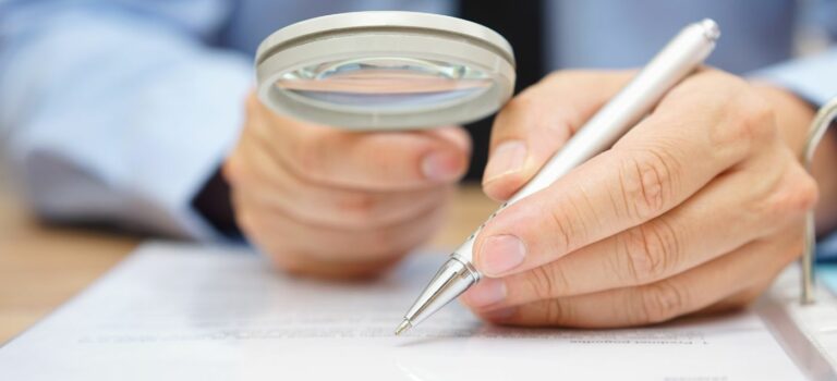 Homme en train de lire un document avec une loupe dans les mains