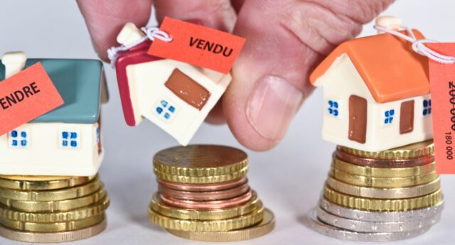 maisons sur des piles d'euros avec étiquettes à vendre et vendu