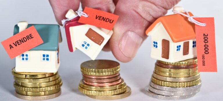 maisons sur des piles d'euros avec étiquettes à vendre et vendu