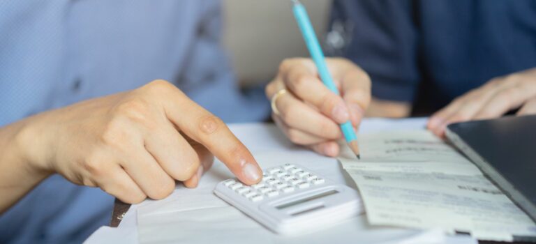 Couple ayant des difficultés financière en train de faire des calculs avec une calculatrice et un crayon à papier.