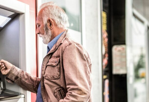 Homme a la retraite tirant de l'argent au distributeur