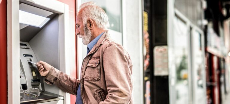 Homme a la retraite tirant de l'argent au distributeur