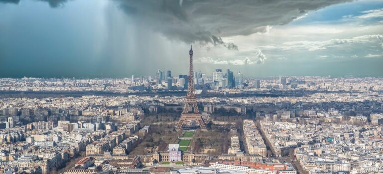Vue d'immeubles à Paris avec la Tour Eiffel, des nuages et ciel gris illustrant le ralentissement de l'immobilier.