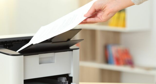 Une main attrapant une feuille de papier sortant de l'imprimante