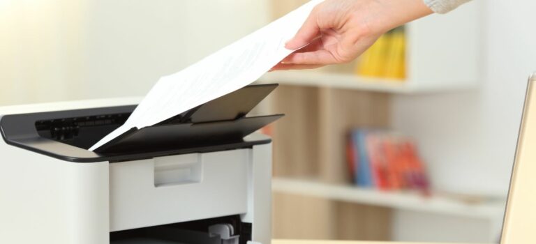 Une main attrapant une feuille de papier sortant de l'imprimante