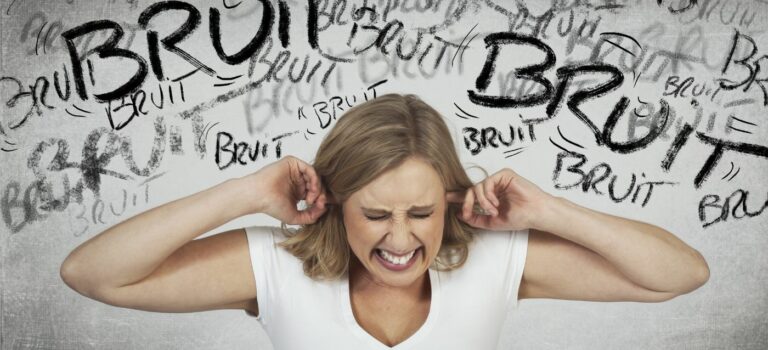 Femme souffrant de nuisances sonores et se bouchant les oreilles devant un mur avec graffitis bruits