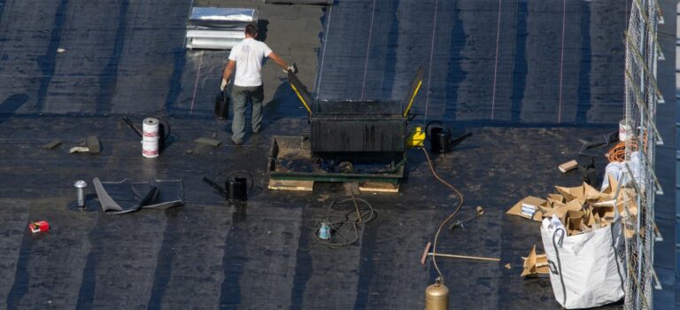 Un couvreur sur le toit d'une maison en train d'effectuer des travaux d'etancheite.