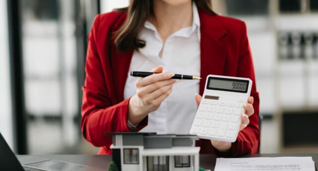 Une femme agent immobilier calculatrice à la main.