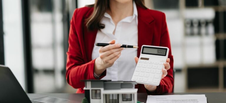 Une femme agent immobilier calculatrice à la main.