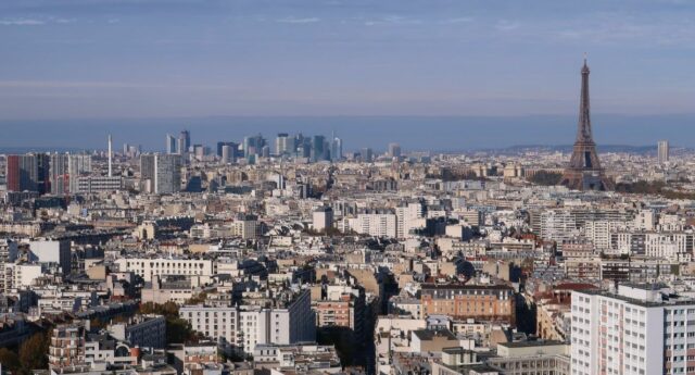 Vue aérienne panoramique sur la ville de Paris et l’agglomération de l’Île-de-France, avec la tour Eiffel et les tours du quartier de La Défense au loin