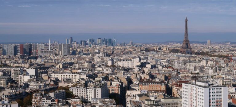 Vue aérienne panoramique sur la ville de Paris et l’agglomération de l’Île-de-France, avec la tour Eiffel et les tours du quartier de La Défense au loin
