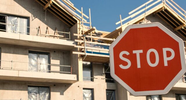 Panneau stop devant des immeubles en construction pour illustrer la crise de l'immobilier neuf