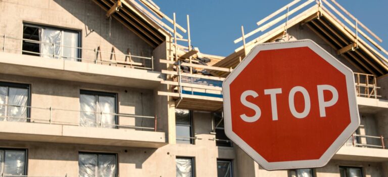 Panneau stop devant des immeubles en construction pour illustrer la crise de l'immobilier neuf