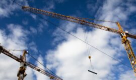 Des grues sur un chantier sur un fond de ciel nuageux pour illustrer la baisse des permis de construire