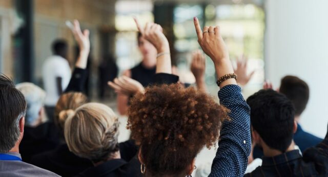 Personnes levant le doigt dans une assemblee generale de copropriete