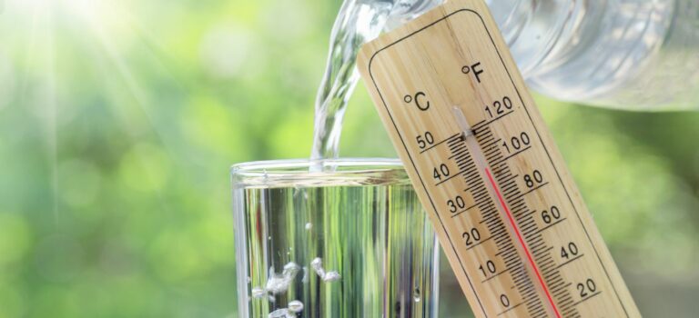 Thermometre pose sur un verre d'eau pour illustrer la canicule