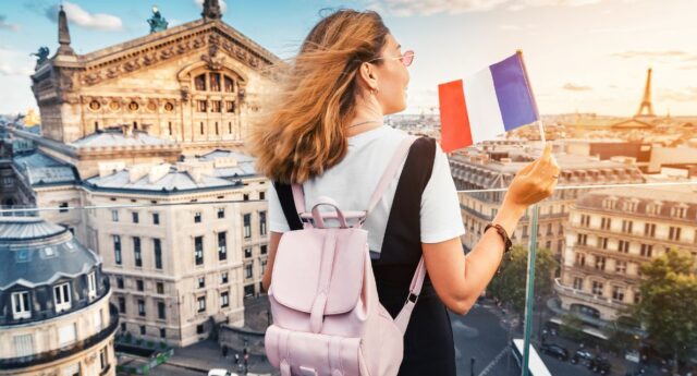 Etudiante avec un drapeau français regardant les immeubles a Paris