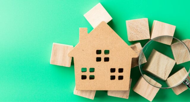 Maison miniature avec un loupe posee dessus pour illustrer l'achat immobilier