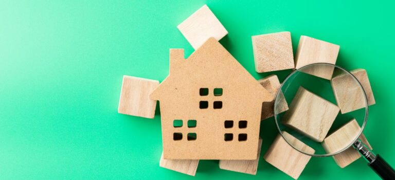 Maison miniature avec un loupe posee dessus pour illustrer l'achat immobilier