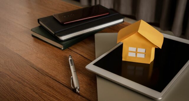 carnet avec une calculatrice et une maison miniature pour illustrer le credit immobilier