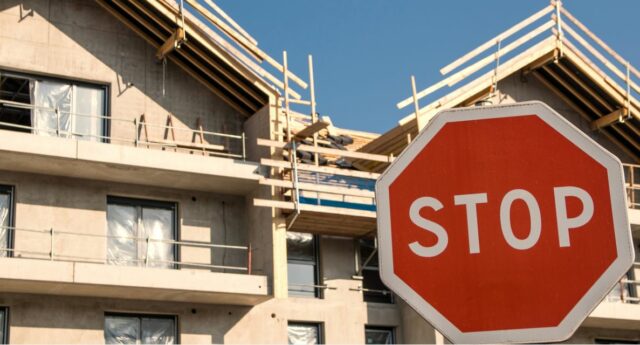 Chantier d'immeubles neufs à l'arret avec un panneau stop devant les immeubles.