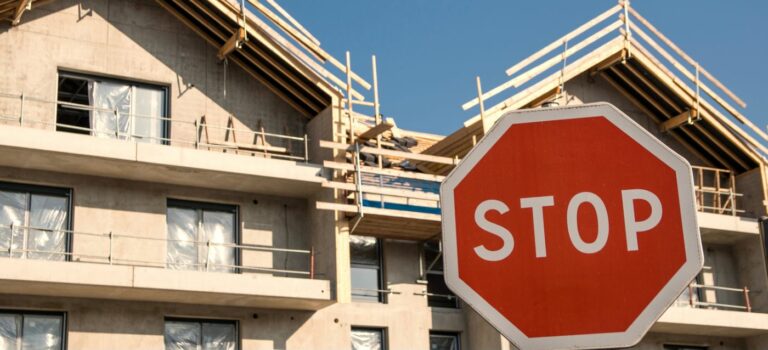 Chantier d'immeubles neufs à l'arret avec un panneau stop devant les immeubles.