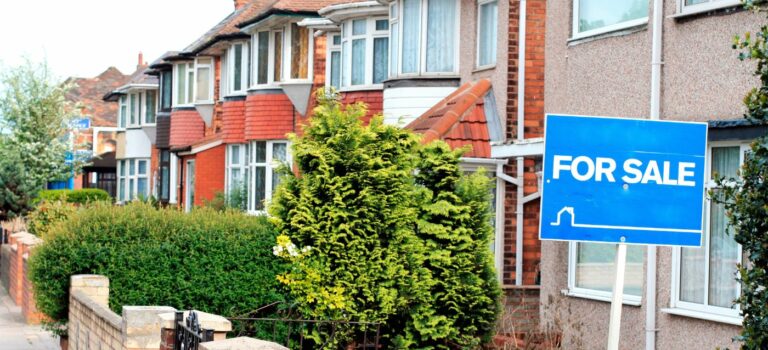 Des maisons anglaise en enfilade avec au premier plan un panneau for sale (a vendre) pour illustrer la crise se l'immobilier au Royaume Uni