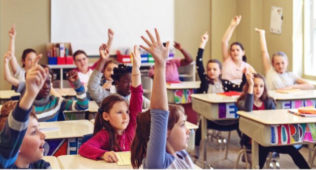 Salle de classe avec des eleves levant la main pour illustrer la rénovation energetique dans les ecoles
