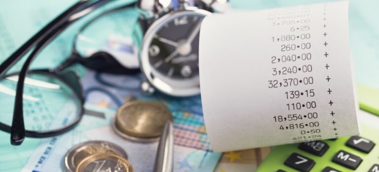 calculatrice, lunettes, montre et ticket de caisse posee sur des billets d'euros