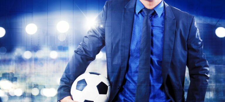 homme en costume cravate sur un terrain de football avec un ballon à la main