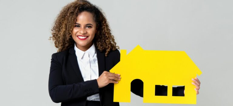 jeune femme souriante tenant un maison miniature entre ses mains