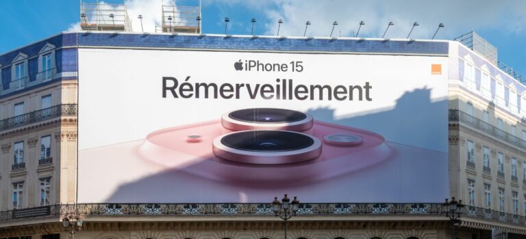 ffiche publicitaire géante Apple iPhone 15 couvrant les échafaudages des travaux de restauration sur la façade d'un immeuble parisien abritant un Apple Store