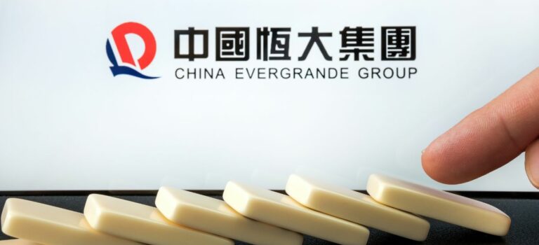 Logo de la société Evergrande au dessus de dominos en train de tomber