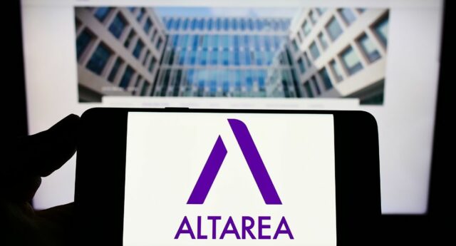 Personne tenant un smartphone dans sa main avec le logo altarea et un immeuble neuf en arriere plan