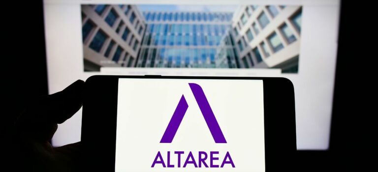 Personne tenant un smartphone dans sa main avec le logo altarea et un immeuble neuf en arriere plan