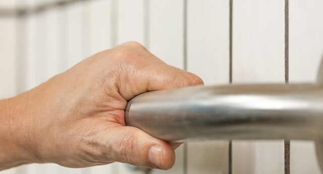 Main se tenant a une barre d'appui dans un salle de bain