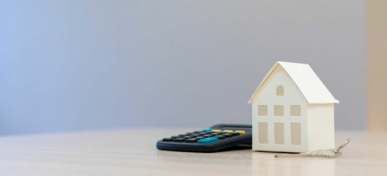 Maison en papier et calculatrice posees sur une table pour illustrer le credit immobilier