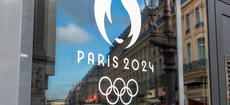 Reflet du Logo Paris 2024 sur une porte vitree a Paris avec des immeubles en toile de fond