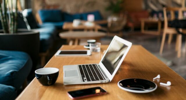 ordinateur portable sur une table basse avec une tasse de cafe pour illustrer l'immobilier de bureaux et le coworking