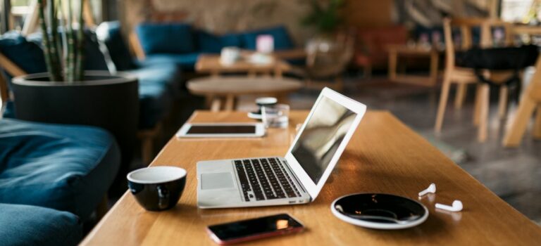ordinateur portable sur une table basse avec une tasse de cafe pour illustrer l'immobilier de bureaux et le coworking